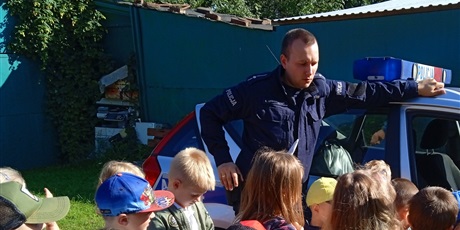 Powiększ grafikę: Policjant przy radiowozie z przedszkolakami
