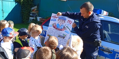 Powiększ grafikę: Policjant demonstruje plakat podziękowanie od przedszkolaków z a wizytę