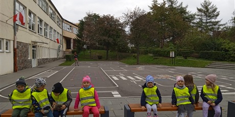 Powiększ grafikę: dzieci siedzą na ławeczkach przy szkole podstawowej nr 56