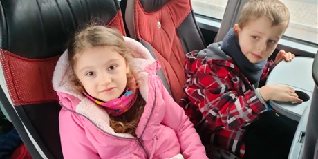 Powiększ grafikę: dziewczynka i chłopiec siedzą w autokarze