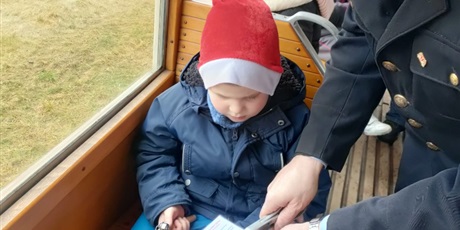 Powiększ grafikę: chłopiec podaje bilet konduktorowi