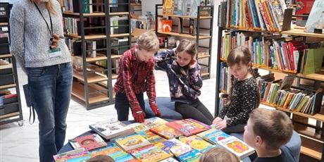 Powiększ grafikę: dzieci oglądają ksiązki w bibliotece