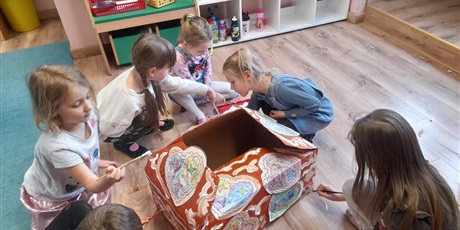 Powiększ grafikę: dzieci dekorują kartonowy domek z piernika