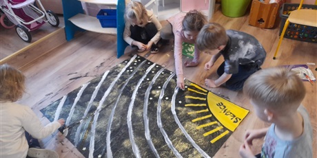 Powiększ grafikę: dzieci domalowują gwiazdy na plakacie