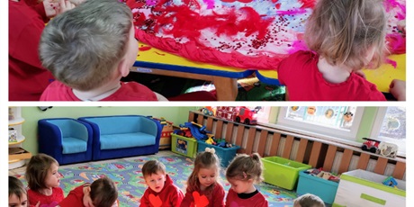 Powiększ grafikę: Walentynki - dzieci w czerwonych ubraniach wyklejają duże papierowe serce ozdobami: piórami, cekinami brokatem, naklejkami
