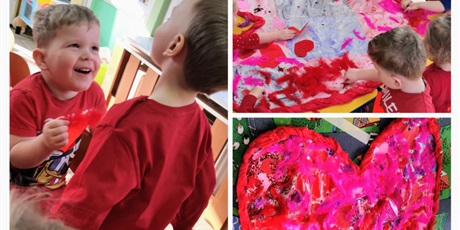 Powiększ grafikę: Walentynki - dzieci w czerwonych ubraniach wyklejają duże papierowe serce ozdobami: piórami, cekinami brokatem, naklejkami