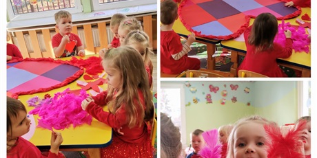 Powiększ grafikę: Walentynki - dzieci w czerwonych ubraniach wyklejają duże papierowe serce ozdobami: piórami, cekinami brokatem, naklejkami
